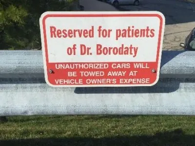 A sign reading Reserved for patients of Dr. Borodaty at the practice's parking spaces.